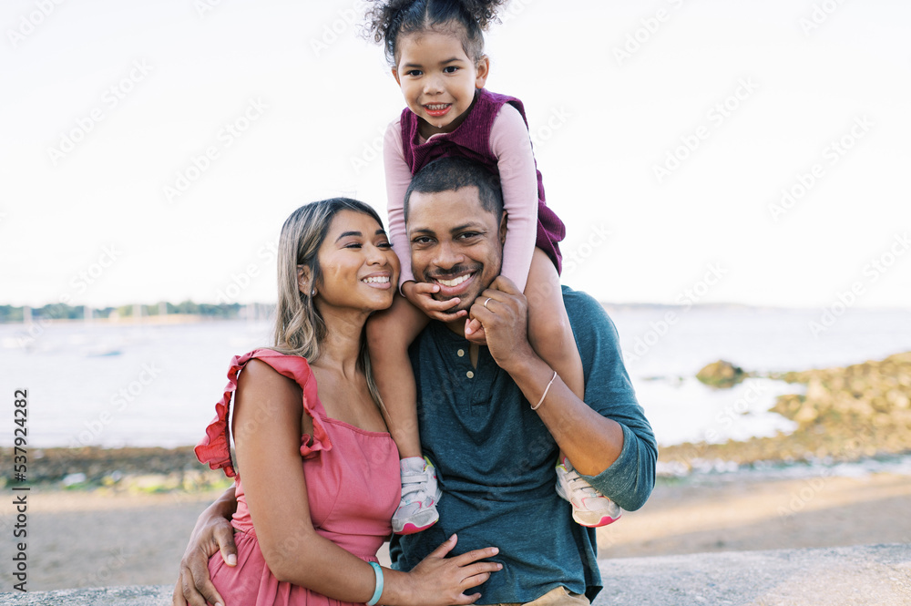 Smiling and happy multiracial family standing by the shore together Smiling and happy multiracial family standing by the shore together