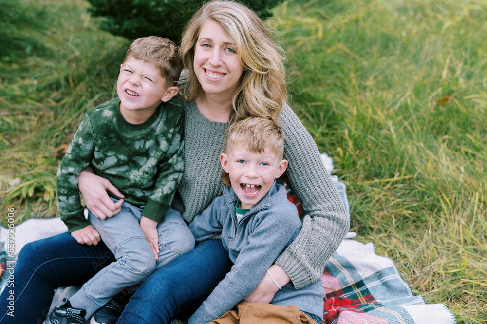 Mother standing with her sons in a field of Christmas trees in winter Mother standing with her sons in a field of Christmas trees in winter