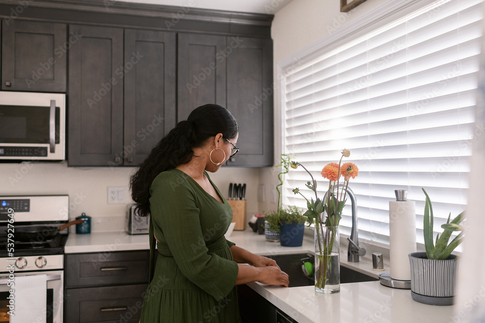 Mixed race woman watering flowers on the sink Mixed race woman watering flowers on the sink