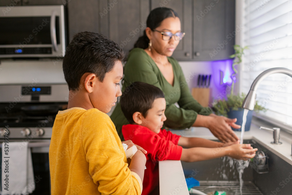 Mother with children washing hands at kitchen sink Mother with children washing hands at kitchen sink