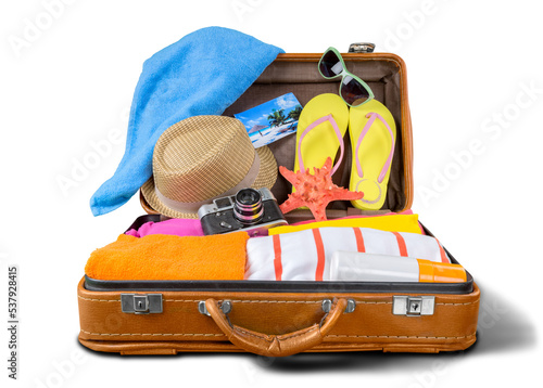 Retro suitcase with travel objects on wooden board on natural background photo