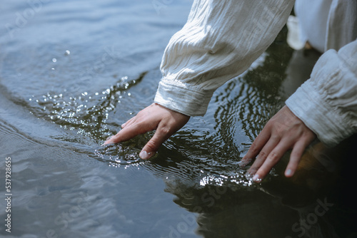 
female hands on the surface of the water photo