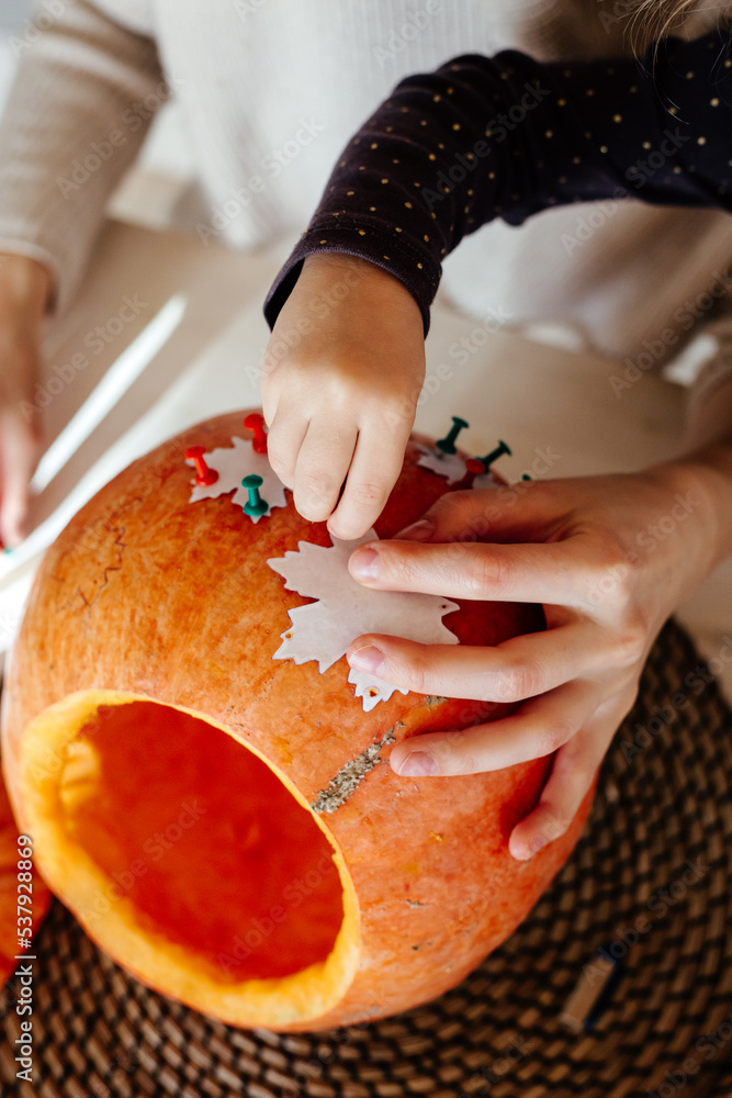 © Sergey Narevskih/Stocksy - Woman with child attaching stencil to pumpkin © Sergey Narevskih/Stocksy - Woman with child attaching stencil to pumpkin