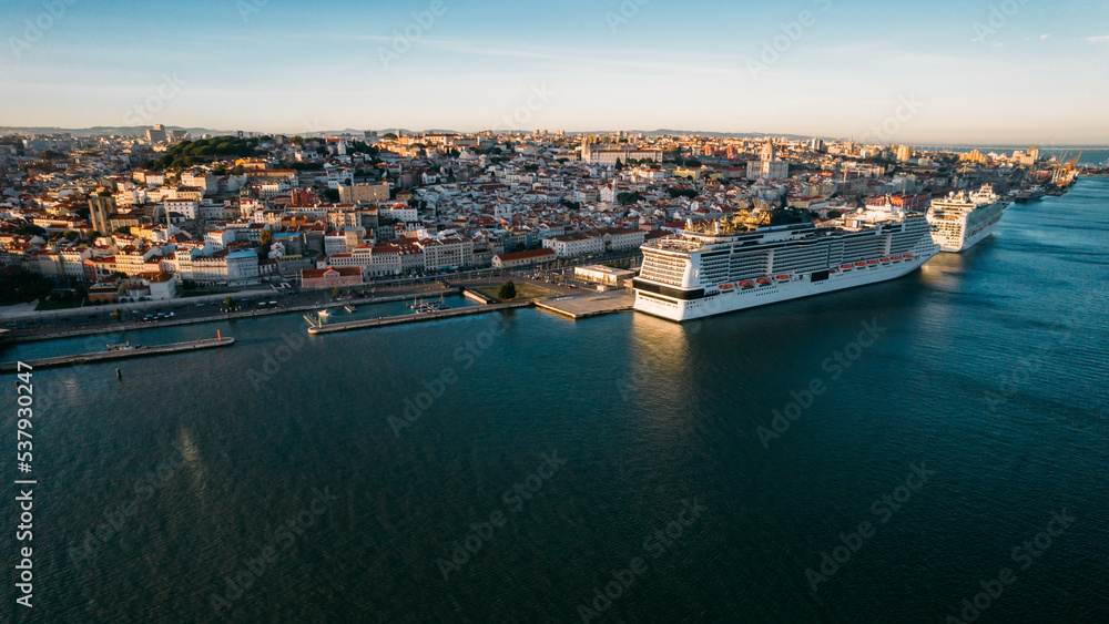aerial drone view of a large cruise ships moored at Lisbon port, Portugal with Lisbon landmarks in the background