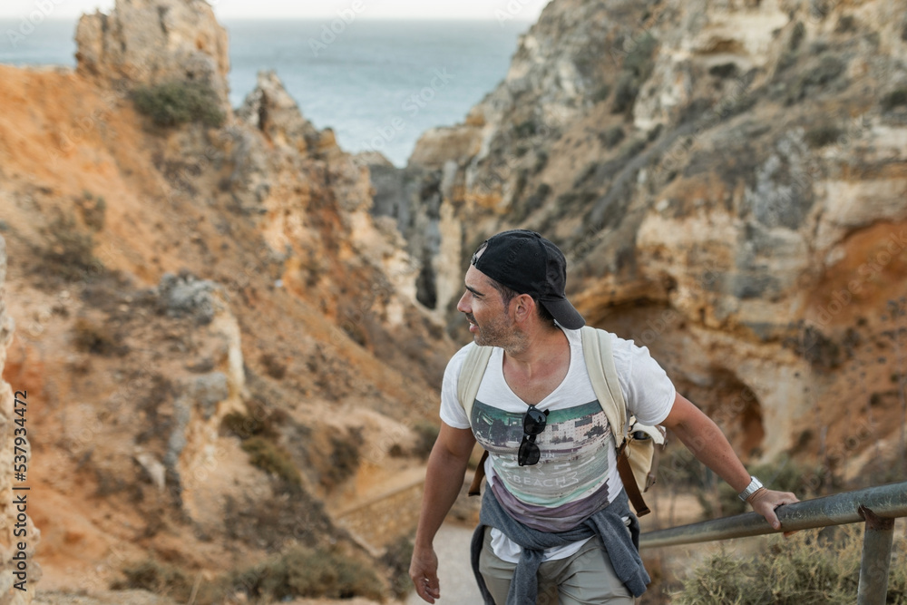 young man climbing the stairs on some cliffs in the sea young man climbing the stairs on some cliffs in the sea