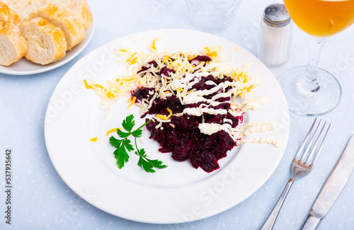 Appetizing vegetable beetroot salad with cheese, fresh parsley and cream sauce on plate in cafe