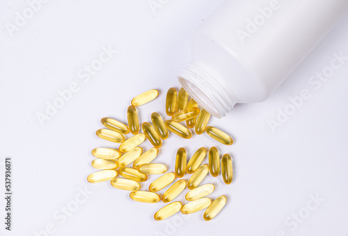 Medical pills spill out of a white jar on an isolated on white background