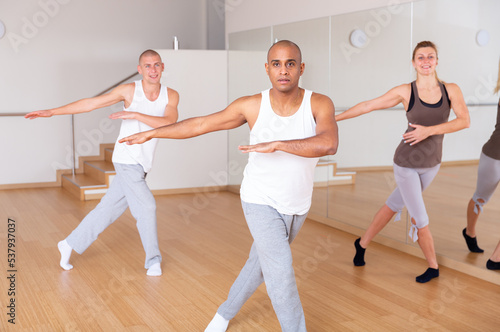 Young adult emotional man dancing during group class in dance center