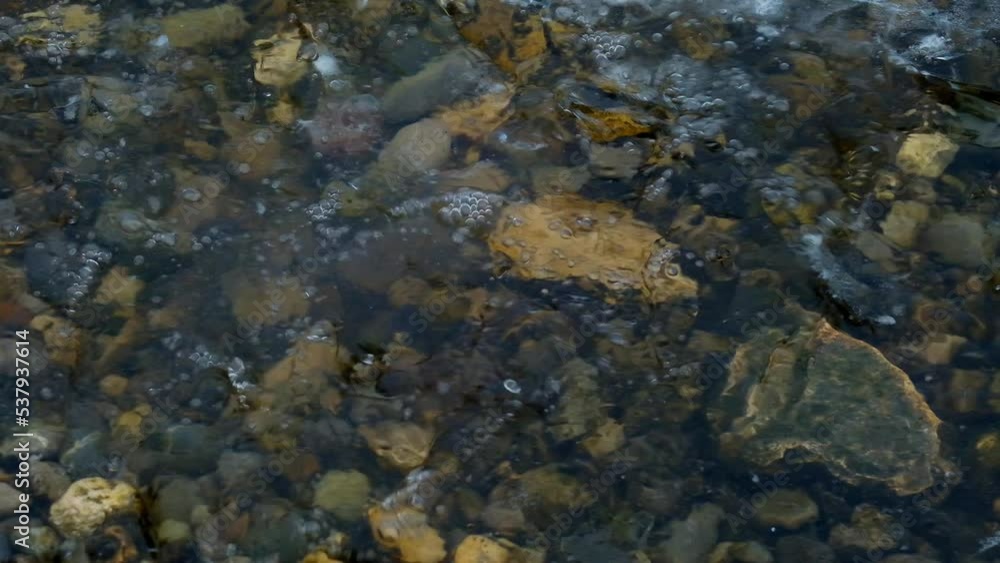 Stones thrown into the water.Splashes close-up.Slow motion.Cold water and ice in a lake with a pebble bottom.Ice and water splashes.Frosty winter weather and nature.4k footage