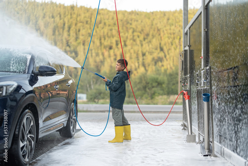 Kid is washing vehicle at manual car wash station