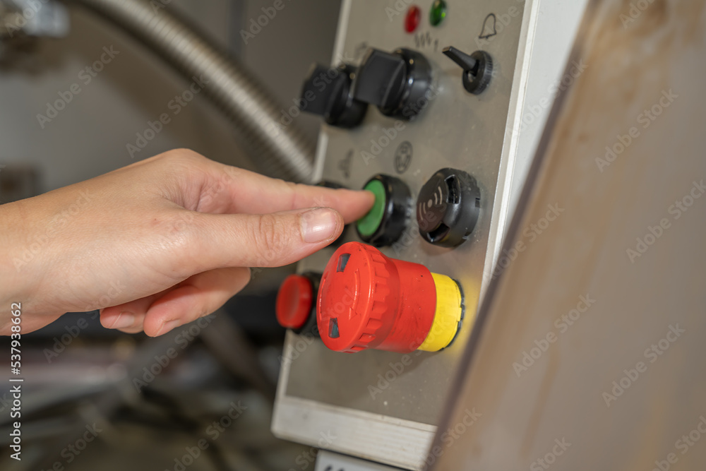 bouton de contrôle d'une machine en usine actionné par une main de femme
