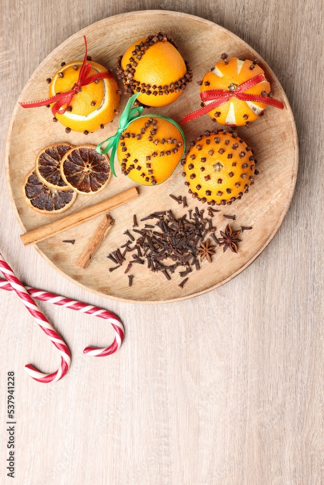 Pomander balls made of tangerines with cloves and candy canes on wooden table, flat lay. Space for text Pomander balls made of tangerines with cloves and candy canes on wooden table, flat lay. Space for text