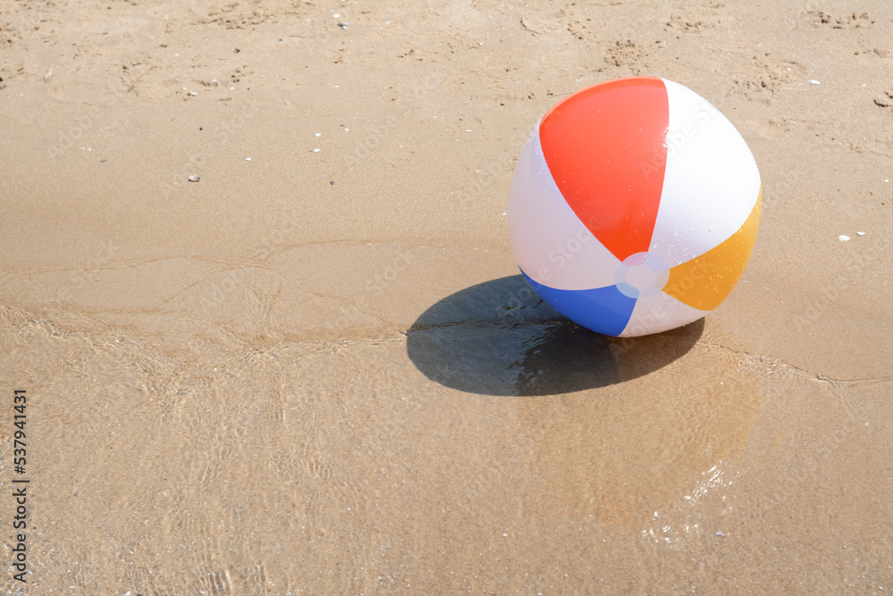 Colorful beach ball on wet sand at seaside, space for text Colorful beach ball on wet sand at seaside, space for text