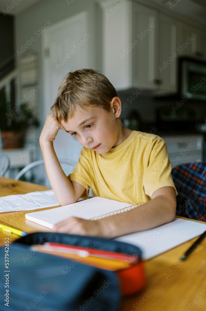 Bored child in yellow shirt doing homework Bored child in yellow shirt doing homework