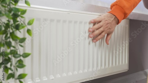 Wallpaper Mural Hand of Person Adjusting Temperature on Thermostat for Control of Heat in Central House Heating System.
The man warms his hands on the heating radiator by the wall.
Cold in the apartment, poor heating Torontodigital.ca