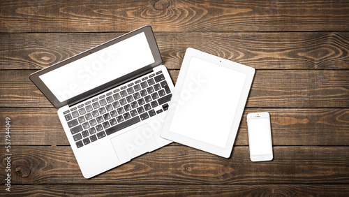 Laptop, smartphone and digital tablet on wooden background