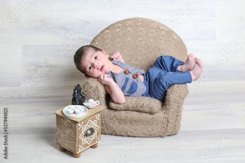 new born baby boy in beautiful dress lying at little chair,tiny stool small toys,face expressions