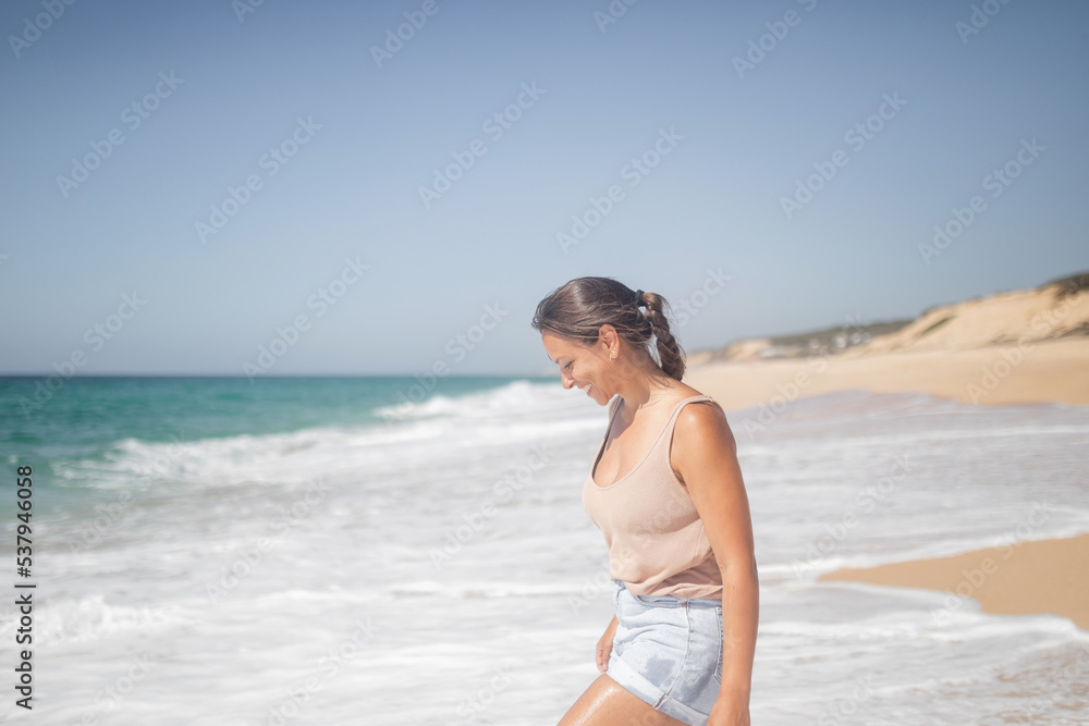 caucasian woman walking along the shore of the beach in summer caucasian woman walking along the shore of the beach in summer