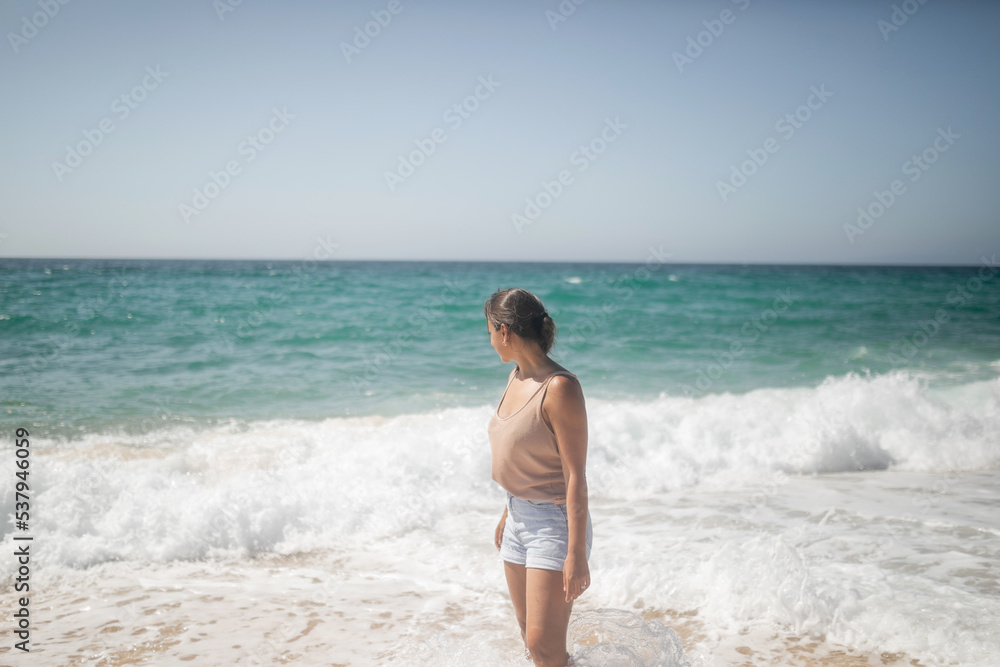 caucasian woman walking along the shore of the beach in summer caucasian woman walking along the shore of the beach in summer