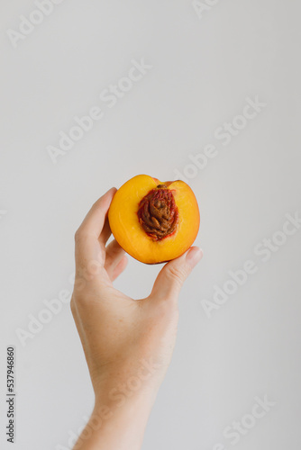 A half of a nectarine in a woman hand on light background