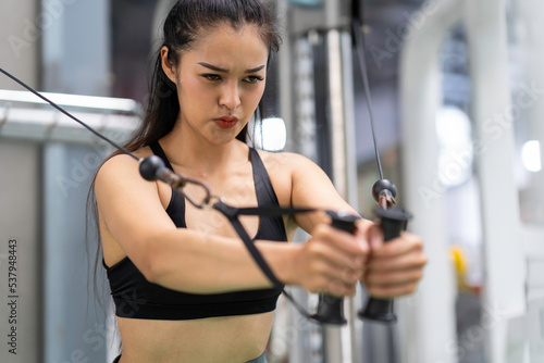 Young Asia lady exercise doing exercise-machine Cable Crossover fat burning workout in fitness class, Sportswoman recreational activity, functional training, healthy lifestyle.