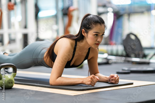 Asian woman doing to "plank". exercise concept.Fitness Asian doing yoga in a gym.Young woman doing pilates, working on abdominal muscles, and exercising to improve core muscle strength in the gym...
