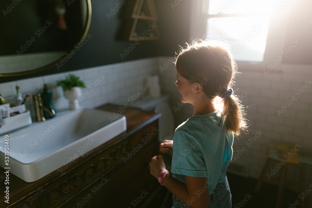 girl combs hair in sunny bathroom girl combs hair in sunny bathroom