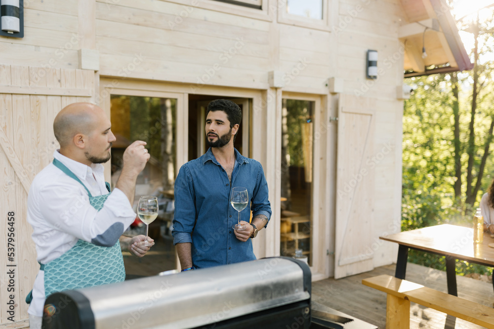 Two Men Preparing Barbecue Outdoors Two Men Preparing Barbecue Outdoors