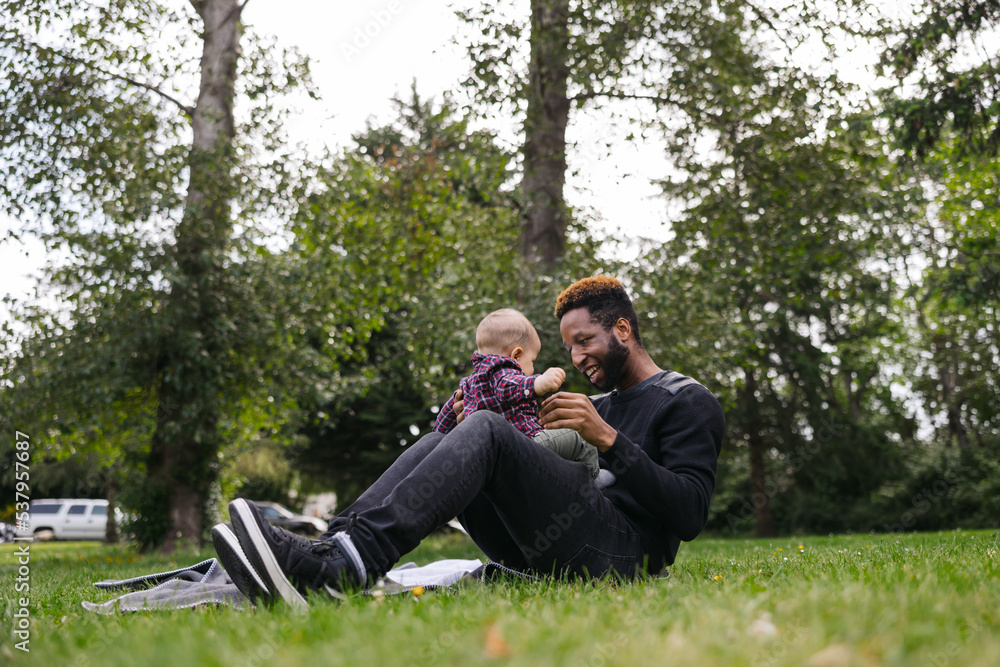 Dad holding baby son on blanket in green grass. Dad holding baby son on blanket in green grass.