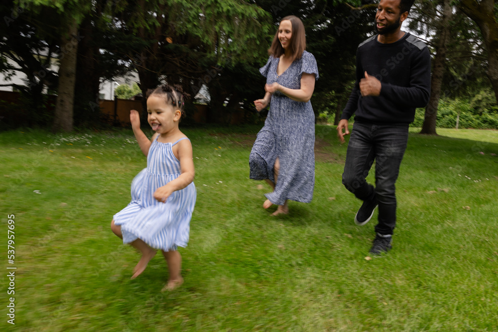 Parents and daughter playing together outside in nature park.