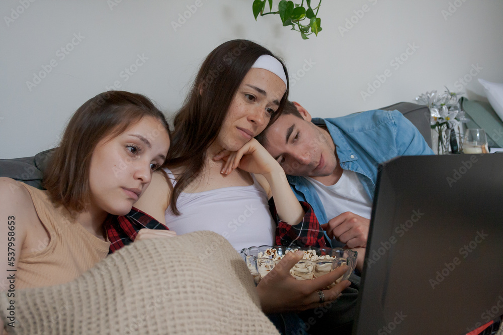 Three young friends watching a movie on the Laptop Three young friends watching a movie on the Laptop