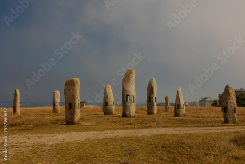 Megaliths stone pillars stand alone in a field with yellow grass and blue sky