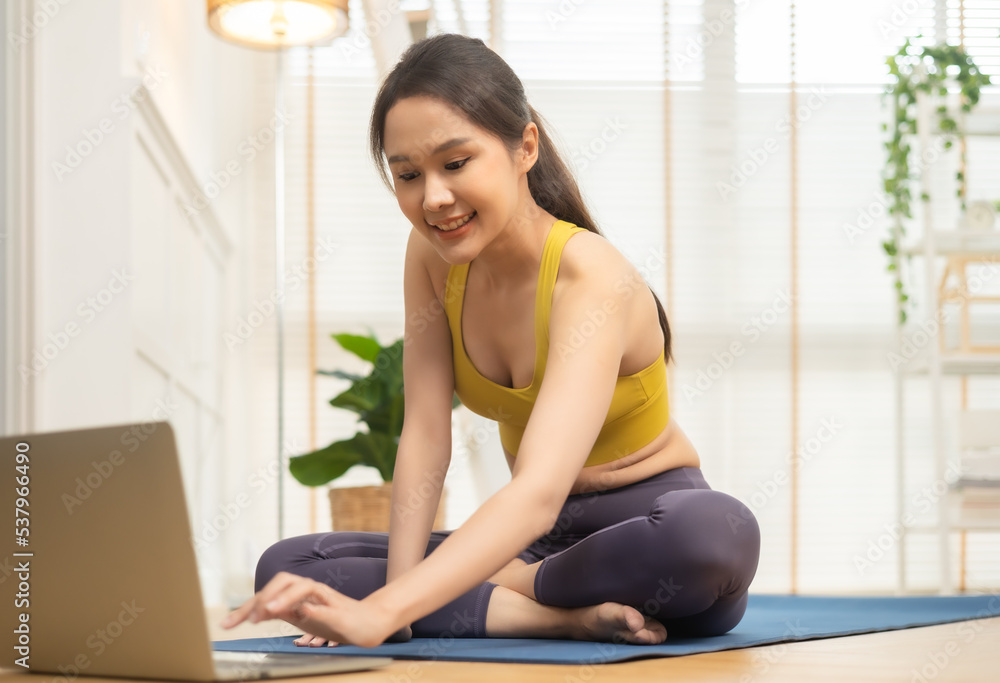 Young Asian woman doing yoga stretching yoga at home.Happy people stay home, doing aerobic exercise at living room Girl doing lockdown activity, workout with trainer for health in house. Young Asian woman doing yoga stretching yoga at home.Happy people stay home, doing aerobic exercise at living room Girl doing lockdown activity, workout with trainer for health in house.