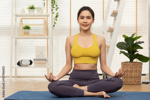 Young Asian woman doing yoga stretching yoga at home.Happy people stay home, doing aerobic exercise at living room Girl doing lockdown activity, workout with trainer for health in house.