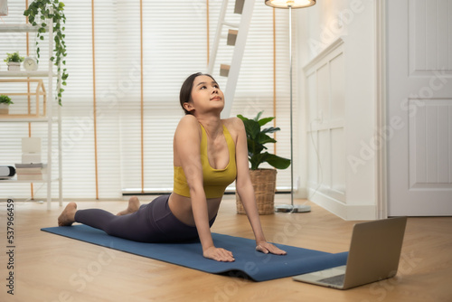 Young Asian woman doing yoga stretching yoga at home.Happy people stay home, doing aerobic exercise at living room Girl doing lockdown activity, workout with trainer for health in house.