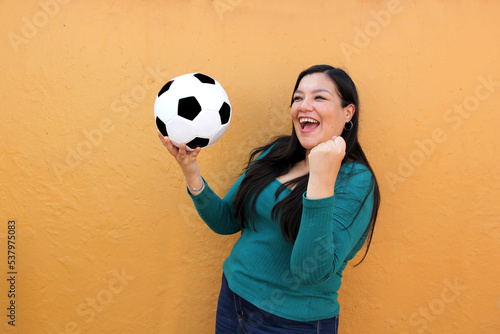 Latino adult woman plays with a soccer ball very excited that she is going to see the World Cup and wants to see her team win