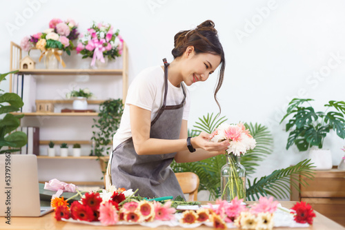 Florist concept  Female florist arranging colorful flowers in vase with happiness in flower shop