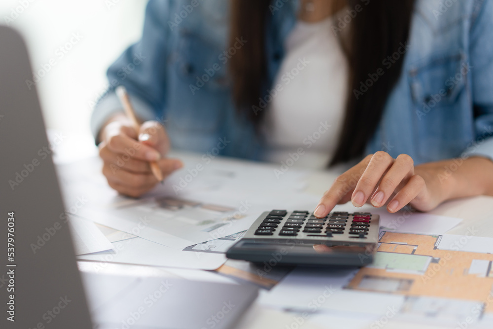 Design building concept, Female architect is using calculator and sketching house plan on blueprint Design building concept, Female architect is using calculator and sketching house plan on blueprint