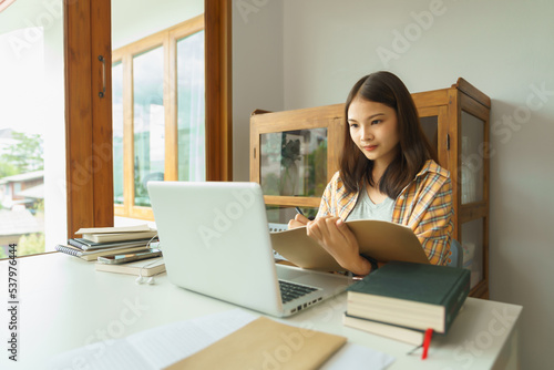 Education and literacy concept, College student girl reading lesson on laptop and taking notes