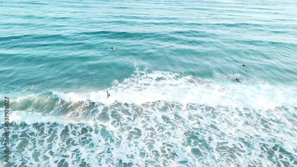 Drone aerial of surfer catching a wave in blue water on a sunny summer day Drone aerial of surfer catching a wave in blue water on a sunny summer day
