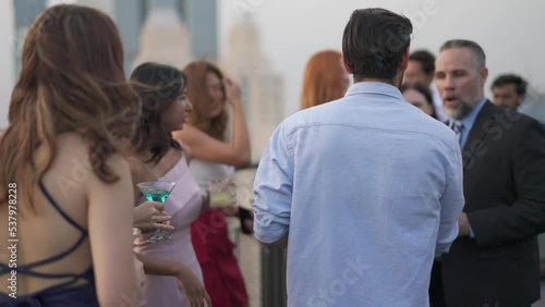 Group of businessmen and businesswomen mingle with each other drinking wine and champagne on a rooftop bar celebrating the successful of company latest deal and hit target goal of the year photo