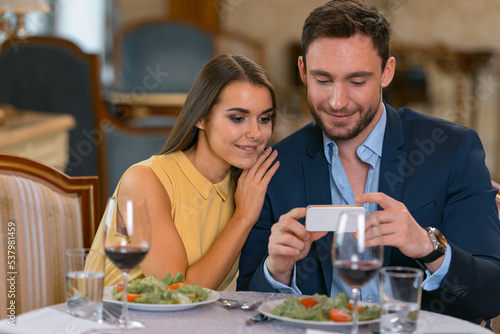 Young couple have romantic dinner in expensive hotel and looking on phone