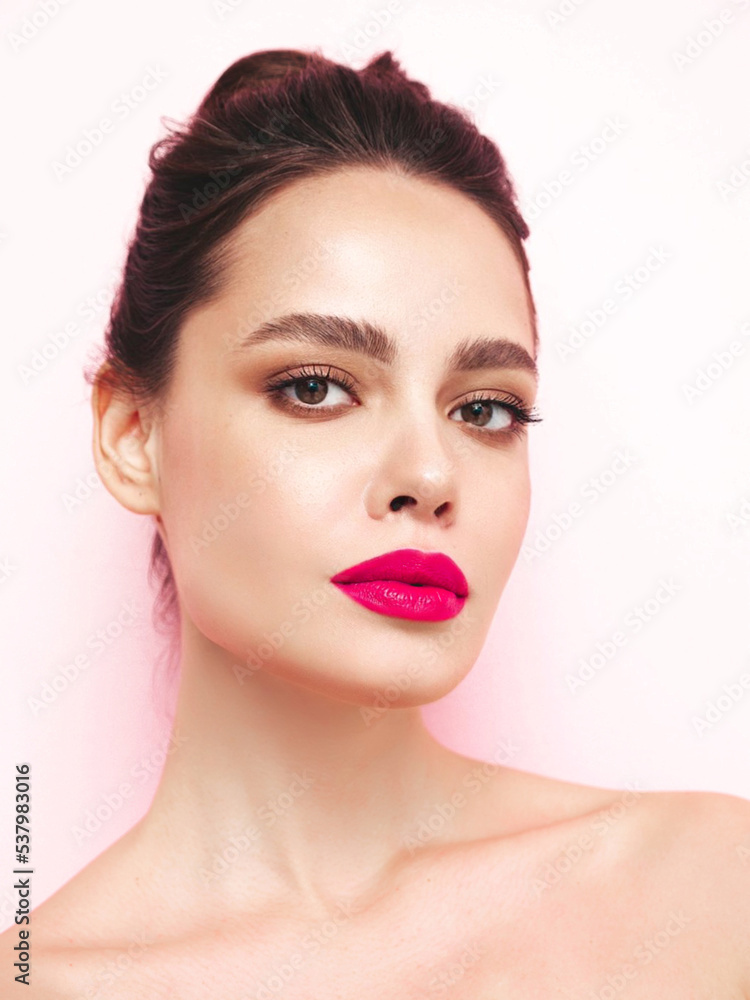 Fashion beauty portrait of young brunette woman with evening stylish makeup and perfect clean skin. Sexy model with hair in a bun posing in studio near white wall. With pink bright natural lips Fashion beauty portrait of young brunette woman with evening stylish makeup and perfect clean skin. Sexy model with hair in a bun posing in studio near white wall. With pink bright natural lips