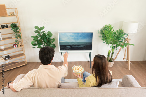 Relaxation concept, Couple holding remote control to changing channel and eating popcorn together