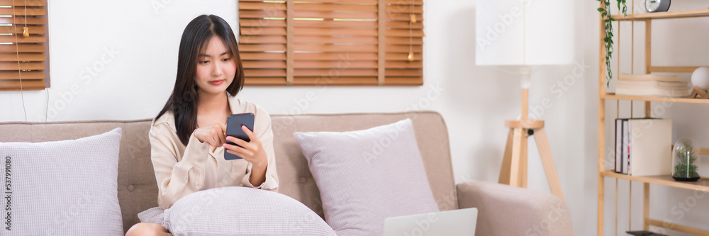 Concept of activity in living room, Asian woman use smartphone to surfing social media on sofa Concept of activity in living room, Asian woman use smartphone to surfing social media on sofa