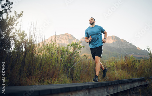 Runner, fitness and man in nature running for outdoor workout, healthy energy and wellness goal with sky mock up background. Sports person with exercise training motivation jogging near the mountains © K Abrahams/peopleimages.com