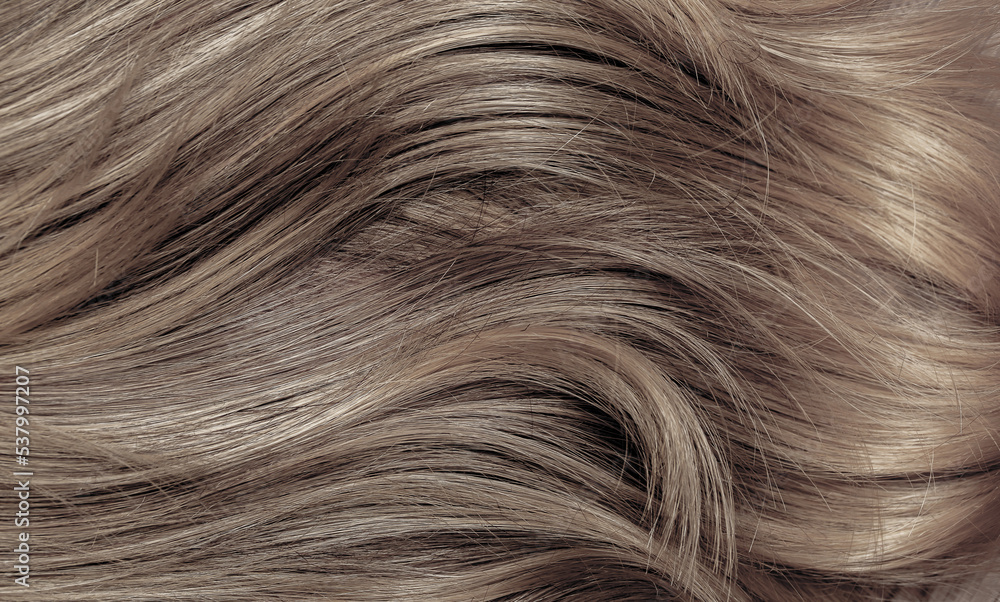 Naklejka premium Brown hair close-up as a background. Women's long brown hair. Beautifully styled wavy shiny curls. Hair coloring. Hairdressing procedures, extension.