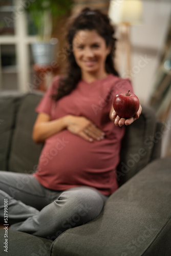 Pregnant woman eating fuit at home. Beautiful pregnant woman holding apple.