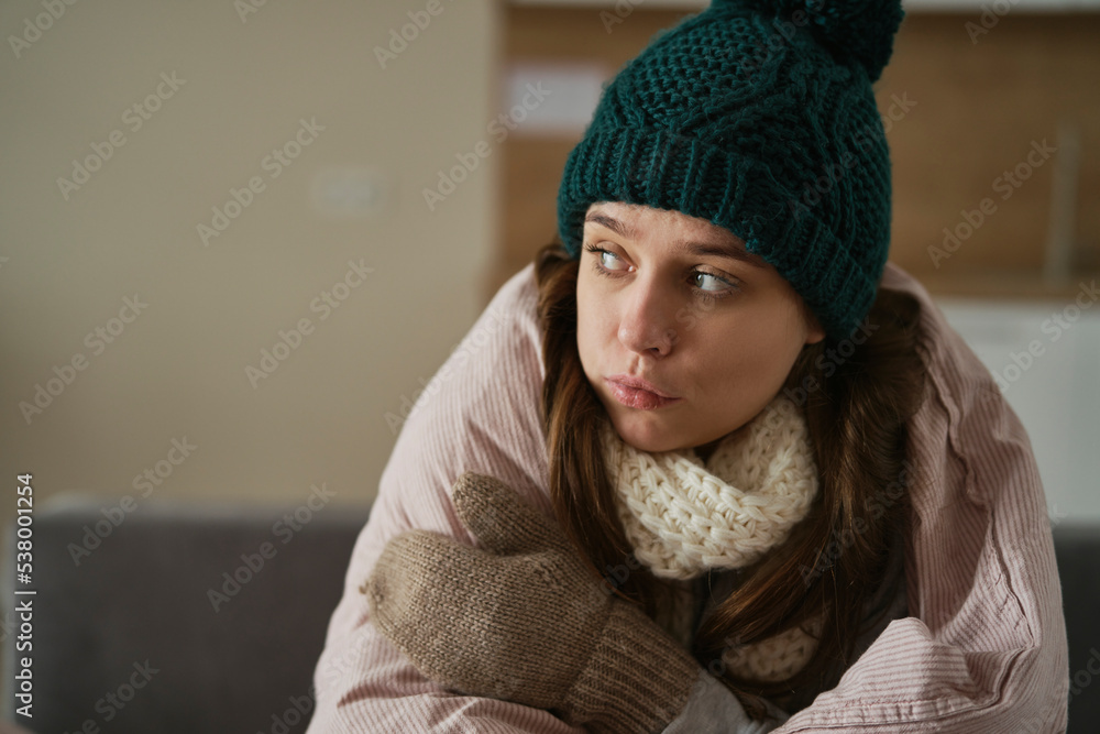 Sadness caucasian woman sitting under duvet wearing in hat at home Sadness caucasian woman sitting under duvet wearing in hat at home