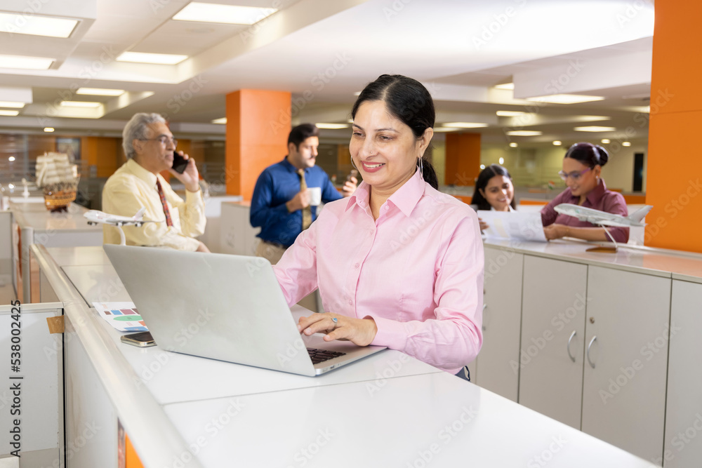 Obraz premium Happy businesswoman using laptop in office.